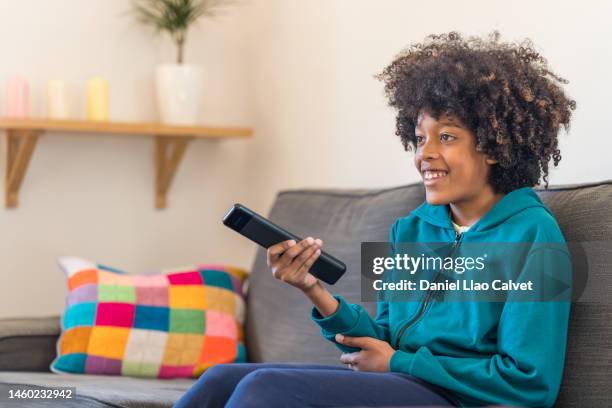 young boy changing channels with a remote control while watching tv - boy watching tv stock pictures, royalty-free photos & images