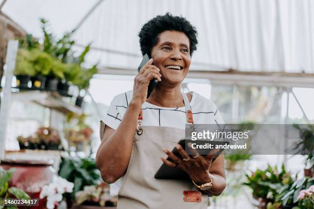 porträt eines floristen, der am telefon verkauft - aushilfsverkäufer stock-fotos und bilder