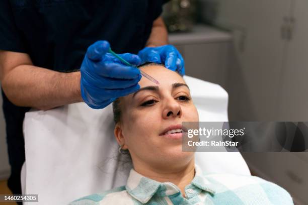 behandlung der gesichtsästhetik - surgeon holding needle stock-fotos und bilder