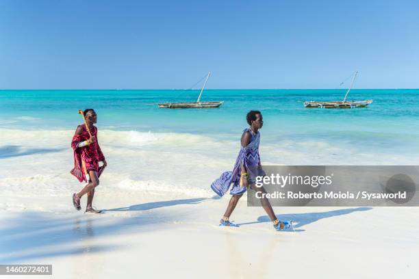 two young maasai men walking on idyllic beach, zanzibar - jambiani stock pictures, royalty-free photos & images