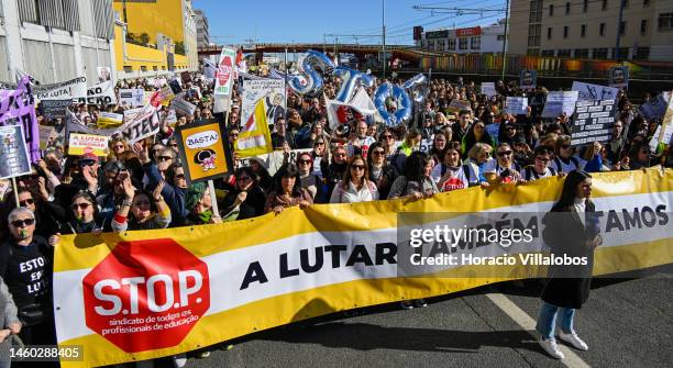 Teachers hold protest signs as they march behind a banner from the Ministry of Education to Belem Presidential Palace to protest for better working...