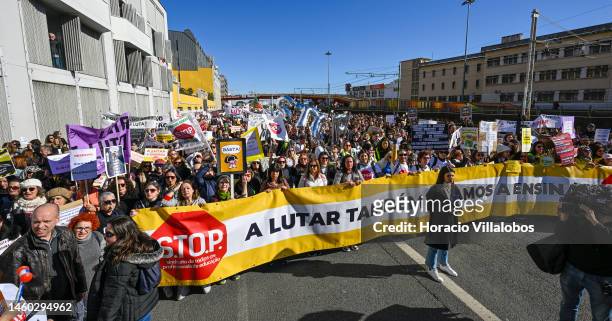 Teachers hold protest signs as they march behind a S.TO.P banner from the Ministry of Education to Belem Presidential Palace to protest for better...