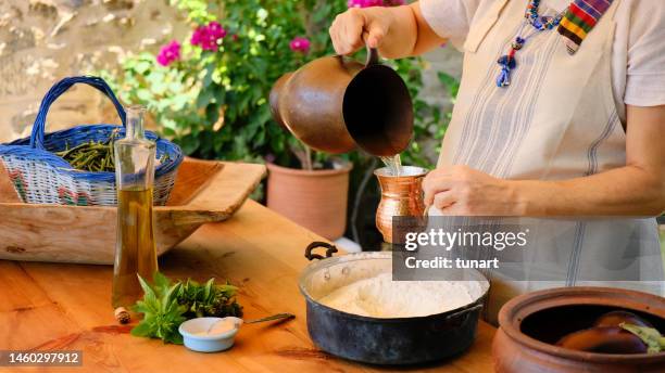 mediterrane frau gießt wasser auf teig - griechische küche stock-fotos und bilder