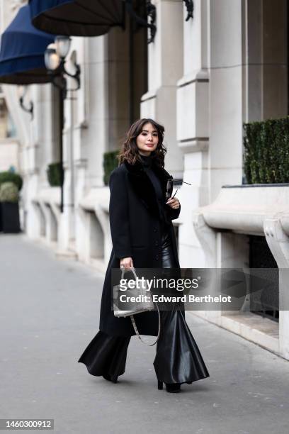 Heart Evangelista wears a black turtleneck pullover, a black long winter coat, a white Hermes bag, black flared leather pants, YSL Saint-Laurent...