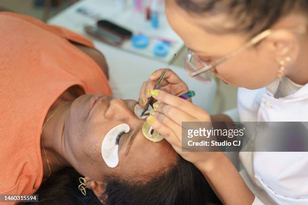 beautician performing eyelash extension strand by strand - cílio stock pictures, royalty-free photos & images