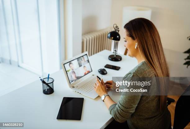 woman working from home, hybrid workspace. woman with earbuds having online meeting - in ear headphones stock pictures, royalty-free photos & images