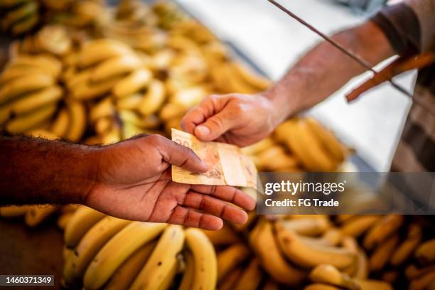 nahaufnahme von menschenhänden, die auf einem straßenmarkt mit brasilianischer währung bezahlen - real stock-fotos und bilder