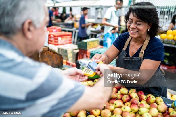 kunde, der auf einem straßenmarkt mit kreditkarte bezahlt - markt verkaufsstätte stock-fotos und bilder