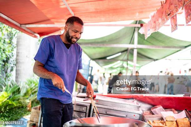 salesman frying "pasty" fried (brazilian pastel) on a street market - 美味食品 個照片及圖片檔