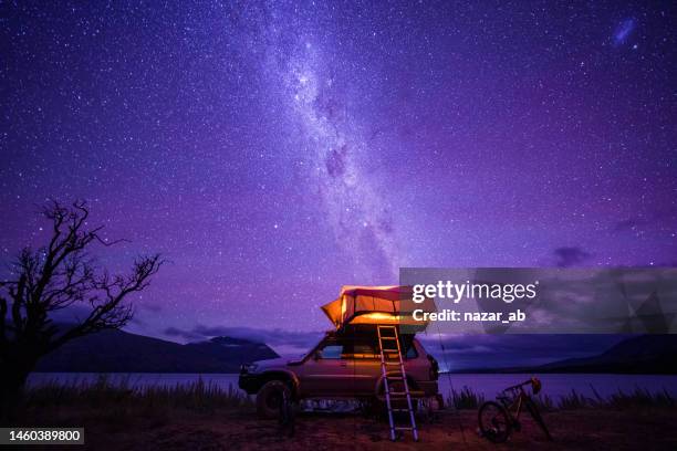 a camper van at nightfall near water body. - purple sky stock pictures, royalty-free photos & images