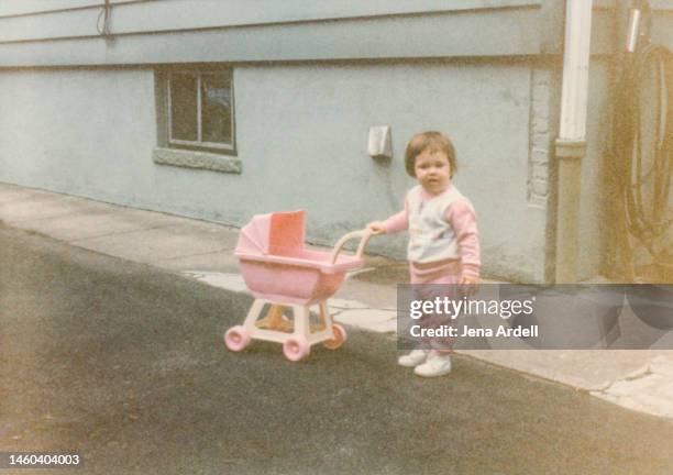 vintage 1980s child playing outside with doll toy stroller, old family photo - american girl doll 個照片及圖片檔