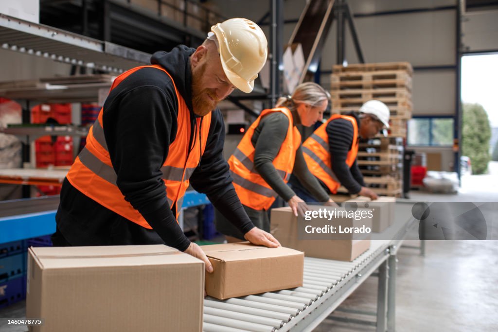 Drei Lagerarbeiter an einer Verpackungs- und Lieferlinie