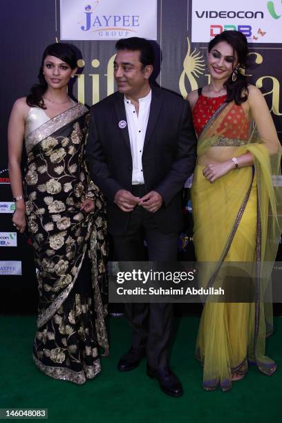 Indian actor Kamal Hassan poses with Bollywood actresses Andrea Jeremiah and Pooja Kumar at the IIFA green carpet event at the 2012 International...