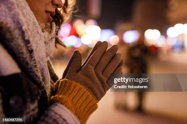 young woman warming her hands while waiting for friends on the city street - rubbing hands together stock pictures, royalty-free photos & images