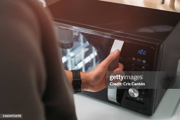 man using microwave - microwave oven stock pictures, royalty-free photos & images