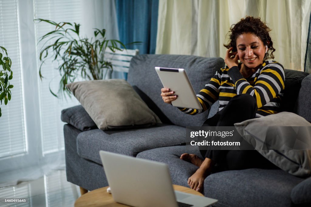 Kopieren Sie die Weltraumaufnahme einer Frau, die ihre Kopfhörer einstellt, während sie über ein digitales Tablet mit einem Freund chattet