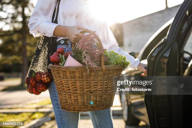 midsection of woman open back door of her car to load groceries from the farmer's market - car isolated doors open stock pictures, royalty-free photos & images