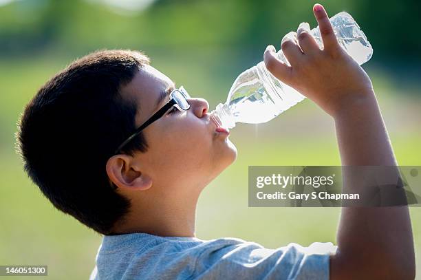 nine year old boy drinking water from a bottle - niño-tomando-agua fotografías e imágenes de stock