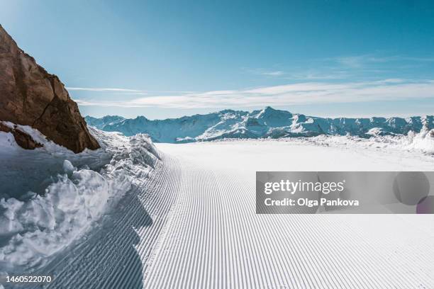 picturesque view of ski slope with fresh ski run track with lines in the mountains, winter background - skipiste stockfoto's en -beelden