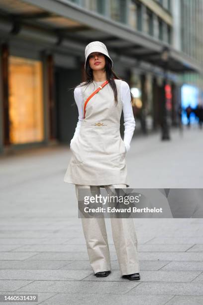 Guest wears a beige embroidered monogram pattern bob from Patou, a beige and white monogram embroidered pattern sleeveless belted dress from Patou, a...