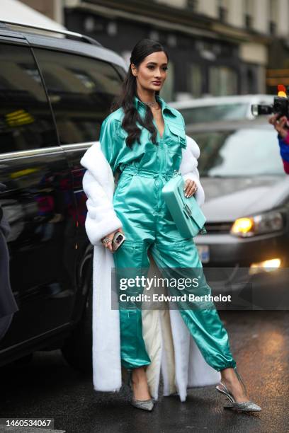 Guest wears a green blue silk jumpsuit from Fendi, a white fur long oversized coat, silver and diamonds earrings, a silver and diamonds necklace,...