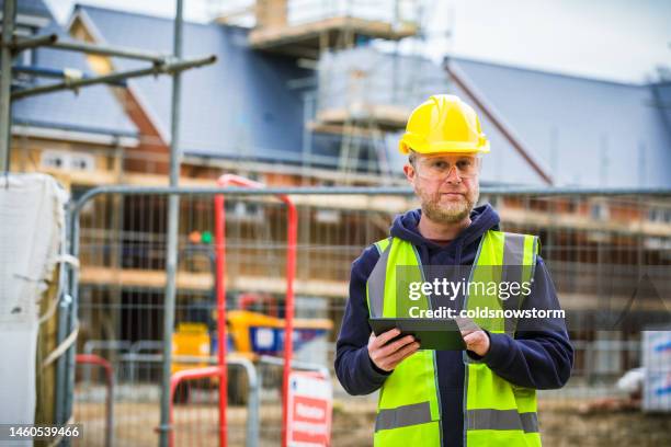 construction worker using digital tablet on building site - real estate developer stock pictures, royalty-free photos & images