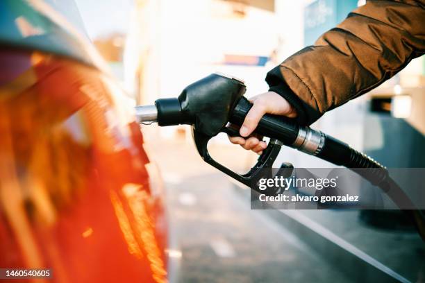 close-up of a hand in a gas pump fueling a car during energy crisis - hose nozzle stock pictures, royalty-free photos & images