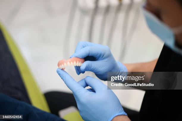 dentist holding a denture - dentures stock pictures, royalty-free photos & images