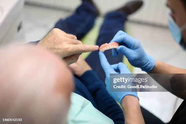 älterer mann in einer zahnarztpraxis - künstliches gebiss stock-fotos und bilder