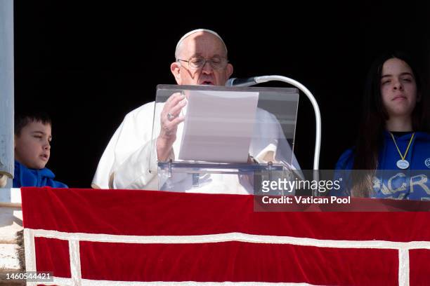 Pope Francis, flanked by two boys, delivers his Sunday Angelus blessing to the faithful from his studio overlooking St. Peter's Square prayer of the...