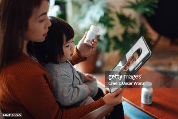 young asian mother and child having online medical consultation with doctor on video call - mother daughter webcam - fotografias e filmes do acervo