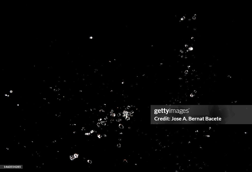 Splashes and drops of water in motion on a black background.