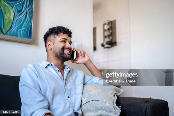 young man talking on the phone at home - gay men latino stock pictures, royalty-free photos & images