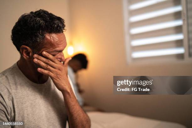 mature gay man sad after arguing with boyfriend in bedroom at home - boyfriend crying stock pictures, royalty-free photos & images