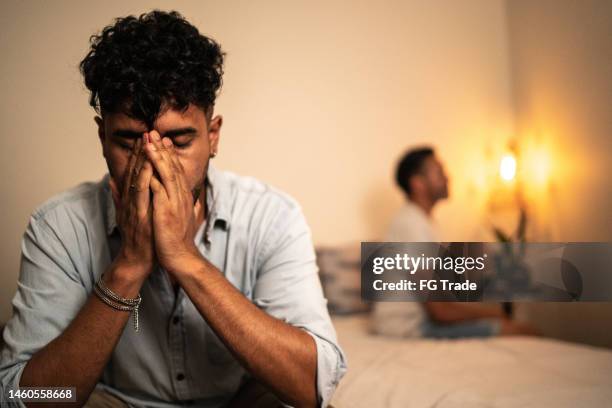 young gay man disappointed with her boyfriend in the bedroom at home - relatieproblemen stockfoto's en -beelden