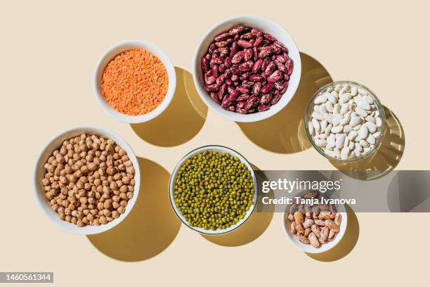 various kinds of vegan protein sources on beige background. nuts and legumes (green mung beans, chick-pea, red lentil, kidney bean, almonds, hazelnuts). flat lay, top view - linse stock-fotos und bilder