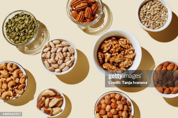 pattern of various nuts on beige. healthy eating concept. pecan, brazil nut, walnut, almonds, hazelnuts, pistachios, cashews. top view, flat lay. - cashews stock pictures, royalty-free photos & images