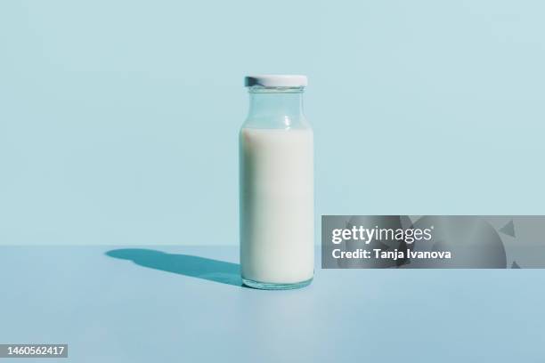 bottle of organic fresh milk on blue background. dairy, grow and drink concept. minimal style, copy space. - bottiglia del latte foto e immagini stock