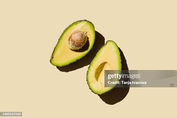 fresh ripe green avocado fruit halves on beige background. healthy food, diet and detox concept. flat lay, top view, copy space - avocado stockfoto's en -beelden