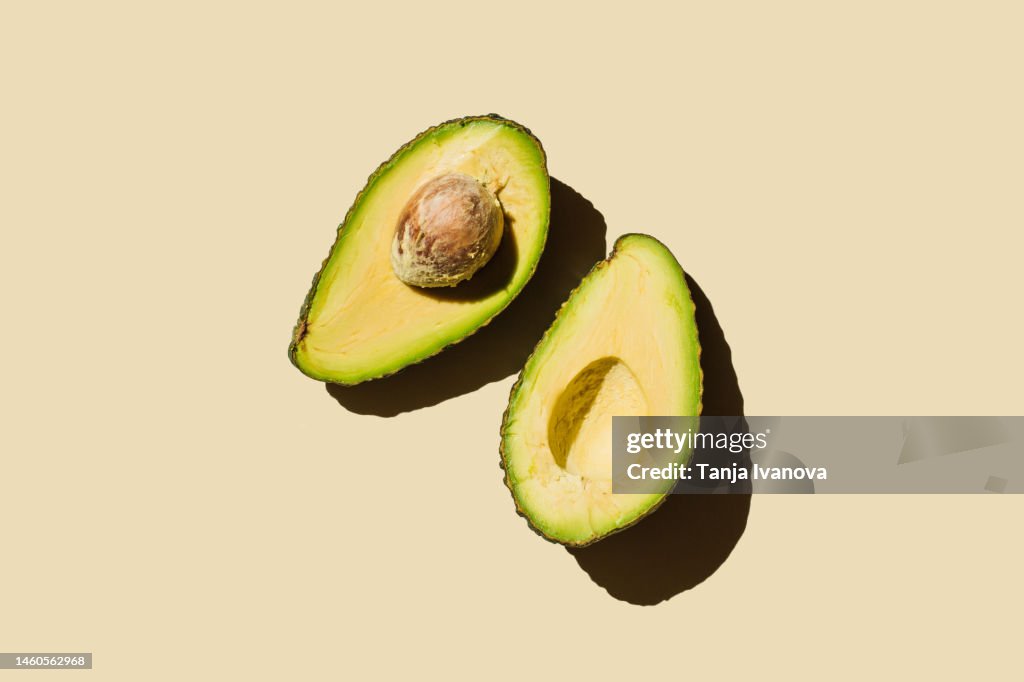 Fresh ripe green avocado fruit halves on beige background. Healthy food, diet and detox concept. Flat lay, top view, copy space