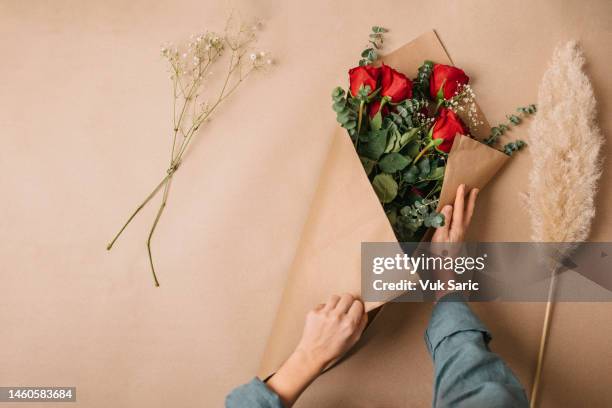 envolviendo un ramo con rosas rojas para el día de la madre - ramo de flores fotografías e imágenes de stock