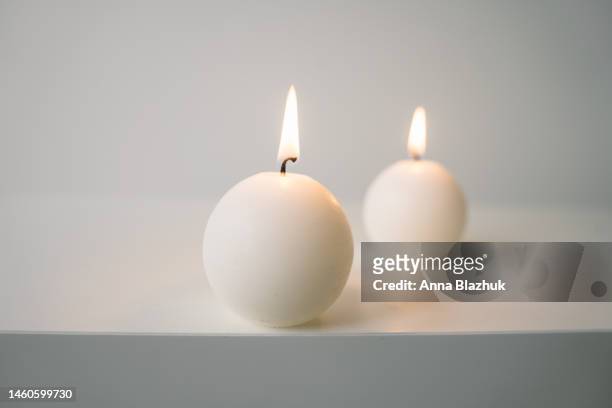 white round candles on white table against white wall - candle white background stock-fotos und bilder