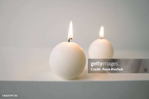white round candles on white table against white wall - candle flame stock pictures, royalty-free photos & images