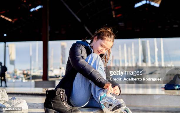 girl putting on inline skates sitting - she can skate stock pictures, royalty-free photos & images