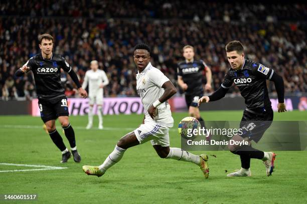 Vinicius Junior of Real Madrid runs with the ball whilst under pressure from Pablo Marin of Real Sociedad during the LaLiga Santander match between...