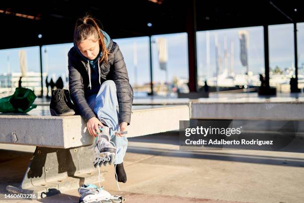 girl putting on inline skates sitting - she can skate stock pictures, royalty-free photos & images