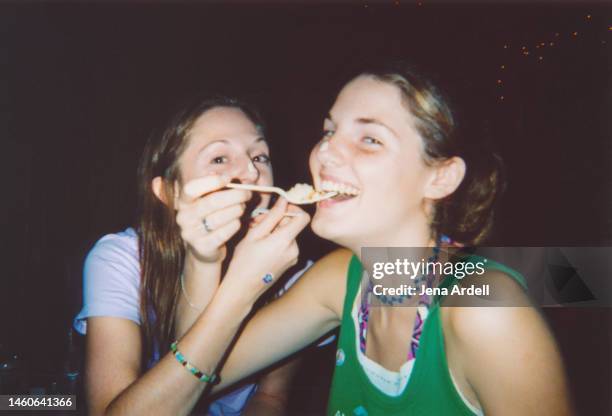 indulgence: best friends having fun eating birthday cake, female friendship on national best friends day - friendship necklace stock-fotos und bilder