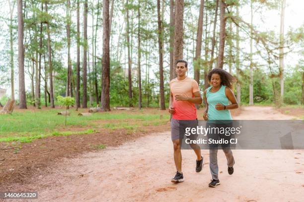 friends training to run on a trail through the woods - etnia caucasiana stockfoto's en -beelden