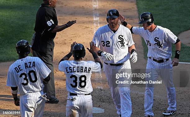 Adam Dunn of the Chicago White Sox is greeted by Alejandro De Aza, Eduardo Escobar and Gordon Beckham after hitting a grand slam home run in the 8th...