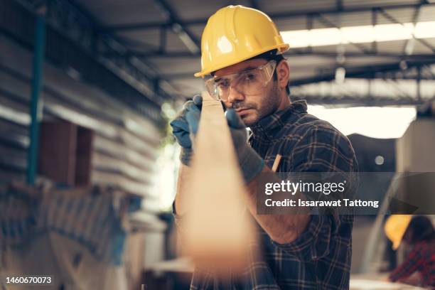 profession, carpentry, woodwork and people concept - carpenter testing wood plank evenness at workshop - handyman stock pictures, royalty-free photos & images